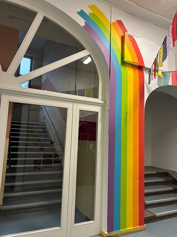 Bild zeigt Malerin, die Regenbogen an Flurwand gestaltet